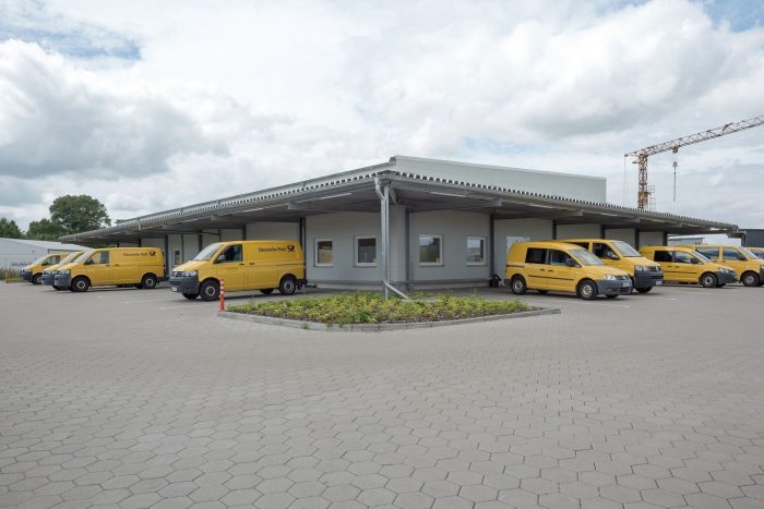Gelbe Transporter vor Industriebau für DHL und Deutsche Post