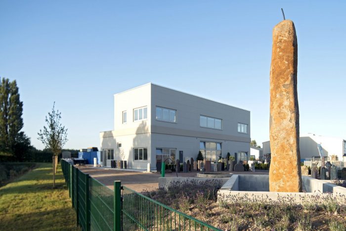 Zweigeschossiges Sommer Gebäude mit gelblichen Wandplatten und Steinstatue