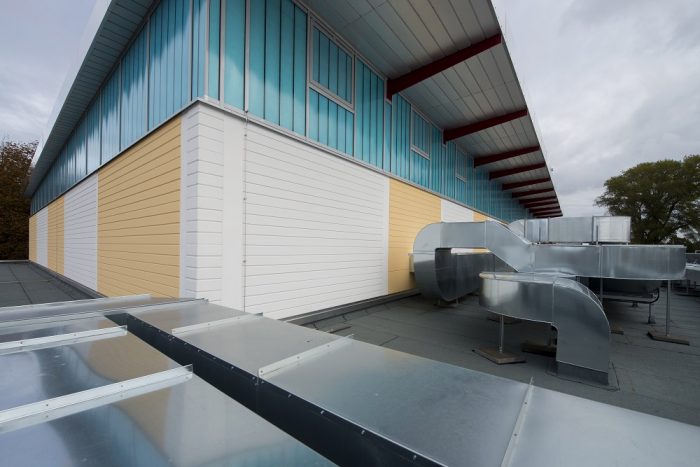 Sporthalle mit weißen und gelben Wandplatten und Luftkanälen in Warnemünde